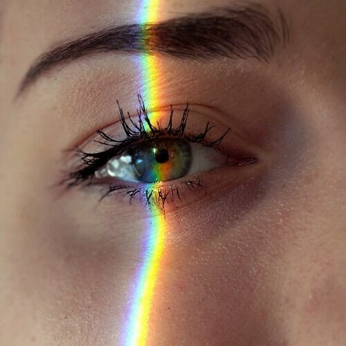 A close up of a woman's eye with a rainbow in it.